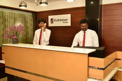 two men in ties standing behind a reception desk at Kohinoor Hotels in Erode