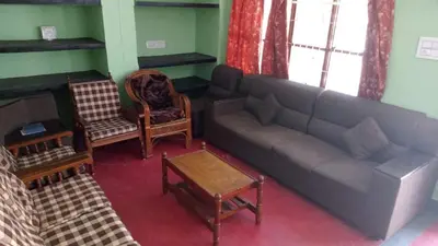 a living room with a couch and a table at The Good Shepherd Cottage in Pollāchi