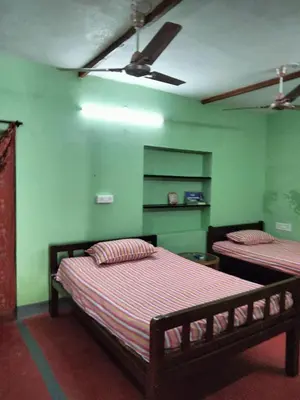 a bedroom with two beds and green walls at The Good Shepherd Cottage in Pollāchi