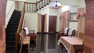a living room with stairs and a table and chairs at Cloud Nine Home Thrissur in Trichūr