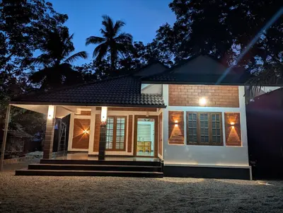 a house with a lit up facade at night at DreamWoods Cottage in Kelakam