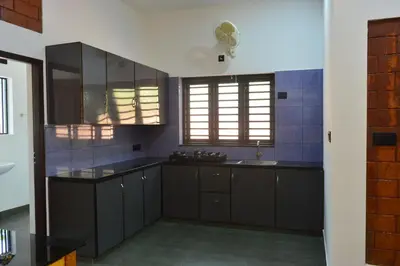 a kitchen with black cabinets and a sink at DreamWoods Cottage in Kelakam