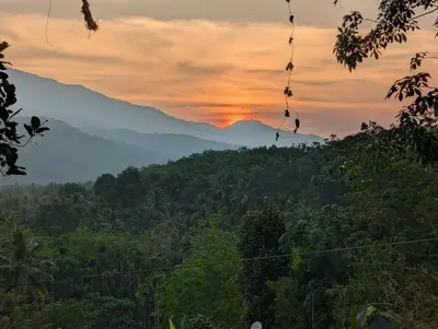 a view of a mountain with a sunset in the background at DreamWoods Cottage in Kelakam