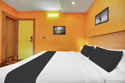 a bedroom with a large white bed with orange walls at Hotel O Kushal Nagar Near KSRTC Bus Stand in Kushālnagar