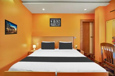 a bedroom with a large bed with orange walls at Hotel O Kushal Nagar Near KSRTC Bus Stand in Kushālnagar