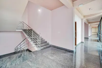 a staircase in a building with white walls and concrete floors at Hotel O Coorg Hanging Bridge in Kushālnagar