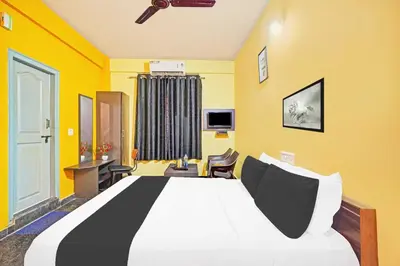 a bedroom with a large bed with yellow walls at Hotel O Coorg Hanging Bridge in Kushālnagar