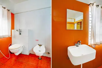 an orange bathroom with a toilet and a sink at Hotel O Mysuru Sand Museum in Mysore