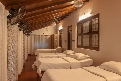 a row of beds in a room with wooden ceilings at The Oneness Living- Seasonal Heritage stay with Tholpaavakoothu nights in Pazhayannūr