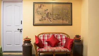 a couch with red pillows sitting under a painting at Bykerstops in Ooty