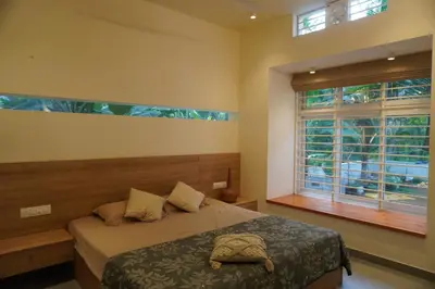 a bedroom with a bed and a large window at Malhar - Your home away from home in Bālūssheri