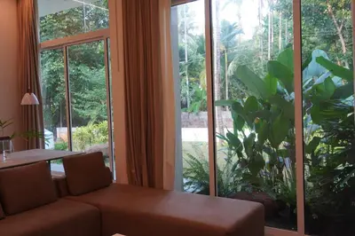 a living room with a couch and a large window at Malhar - Your home away from home in Bālūssheri