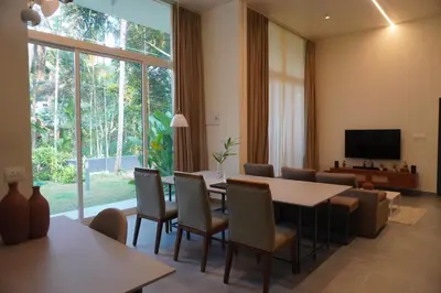 a living room with a table and chairs and a television at Malhar - Your home away from home in Bālūssheri