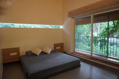 a bedroom with a bed and a large window at Malhar - Your home away from home in Bālūssheri