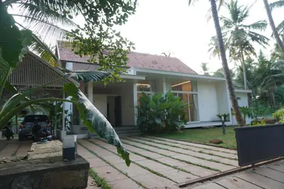 a house with a palm tree in front of it at Malhar - Your home away from home in Bālūssheri