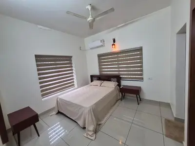 a white bedroom with a bed and two windows at Zainab Apartment in Perintalmanna