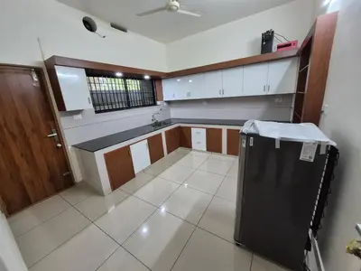 a large kitchen with a black refrigerator in it at Zainab Apartment in Perintalmanna