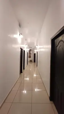 a hallway with white walls and a hallway with black doors at SAF RESIDENCY mukkam in Mukkam