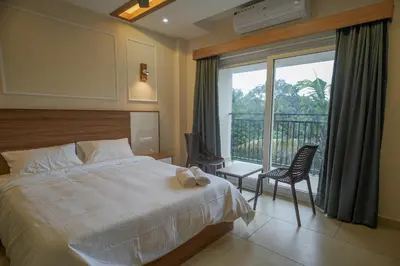a bedroom with a large bed and a balcony at AR Suites Kothamangalam in Kotamangalam