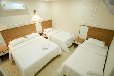 two beds in a hotel room with white sheets at AR Suites Kothamangalam in Kotamangalam