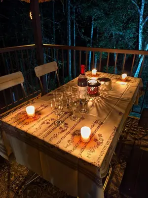 a table with wine glasses and candles on a deck at IRU Homes - Private Family Stay with Pool in Ambalavayal