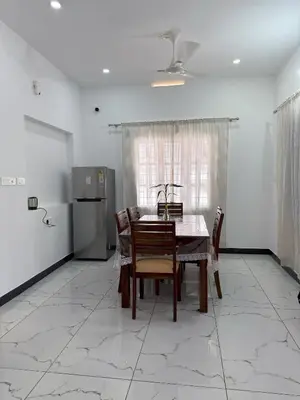 a dining room with a table and chairs and a refrigerator at SRI Villa Rooms in Wayanad - Family Villa Stay with Mountain views in Vayittiri