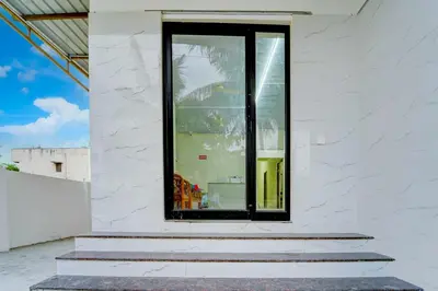 a window on the side of a white building with stairs at Hotel O Coimbatore Peelamedu Railway Station in Coimbatore