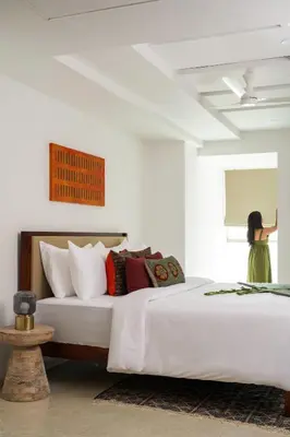 a woman standing in a white bedroom with a bed at Quad One in Kozhikode