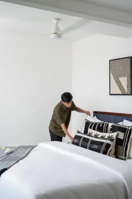 a man is standing next to a large bed at Quad One in Kozhikode