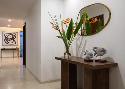 a table with a mirror and a vase with flowers on it at Quad One in Kozhikode