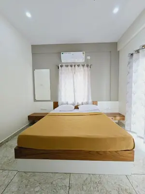 a bedroom with a large bed with a yellow blanket at Nandan Suits in Mysore