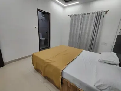 a bedroom with a bed with a yellow sheet on it at Nandan Suits in Mysore