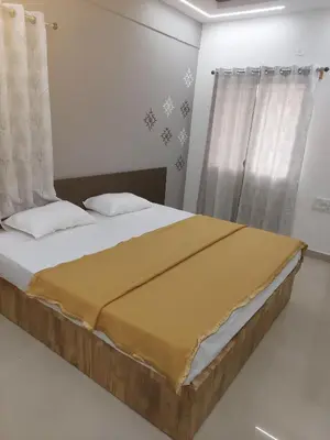 a bedroom with a bed with a yellow blanket on it at Nandan Suits in Mysore