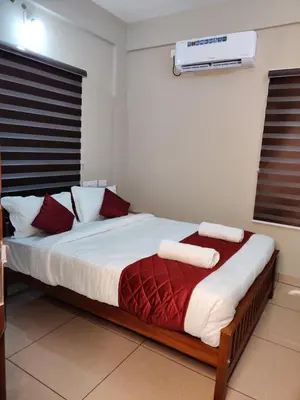 a bedroom with a bed with red and white pillows at Dreams Arcade in Nedumbassery