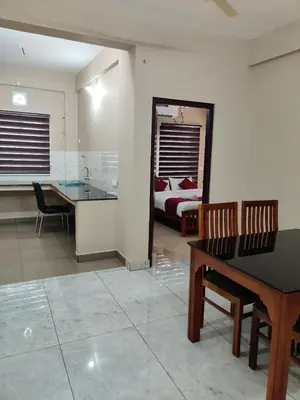 a living room with a dining table and a bedroom at Dreams Arcade in Nedumbassery