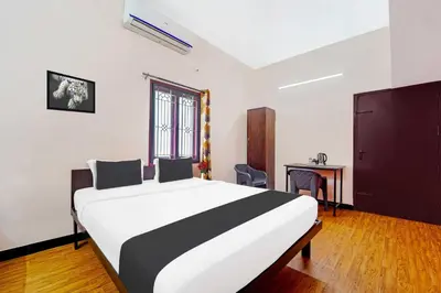 a bedroom with a large bed and a table at Collection O Ganapathy Athipalayam Pirivu Road in Coimbatore