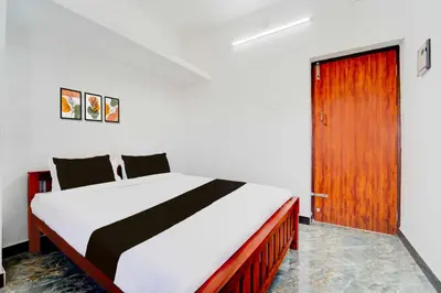 a bedroom with a bed and a wooden door at Collection O Neelambur Near PSG ITech in Irugūr