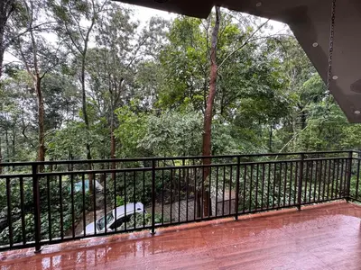 a balcony with a black fence and a car at Aambal Wayanad Pool House Resort by Veda Retreat in Wayanad