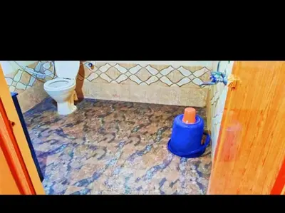 a bathroom with a toilet and a blue bucket at THE DOCkSIDE INN in Madikeri