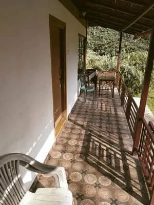 a porch with benches and a table and chairs at THE DOCkSIDE INN in Madikeri