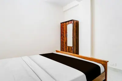 a bed with a wooden headboard in a room at Super Collection O RS Puram North Railway Station Formerly RG Residency in Coimbatore