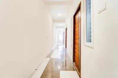 a hallway with white walls and a wooden door at Super Collection O RS Puram North Railway Station Formerly RG Residency in Coimbatore
