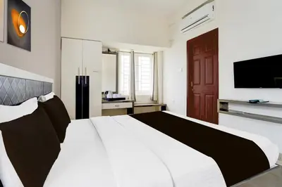 a bedroom with a large white bed and a flat screen tv at Hotel O Ondipudur Bus Terminal Formerly New Paradise Inn in Irugūr