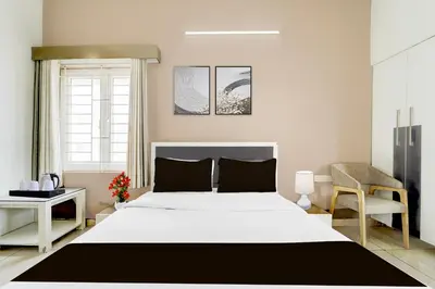 a bedroom with a large white bed and a chair at Hotel O Ondipudur Bus Terminal Formerly New Paradise Inn in Irugūr