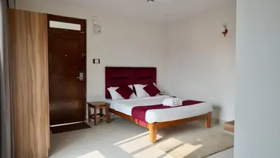 a bedroom with a white bed with a red headboard at Heritage Suites in Mysore