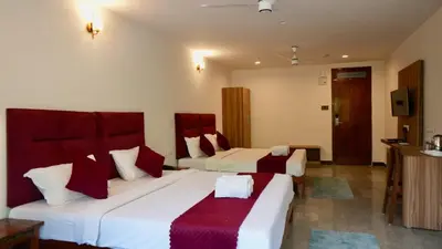 a hotel room with two beds and a television at Heritage Suites in Mysore