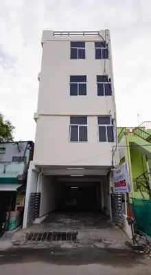 a large white building with a parking garage at Pvt Residency in Palani