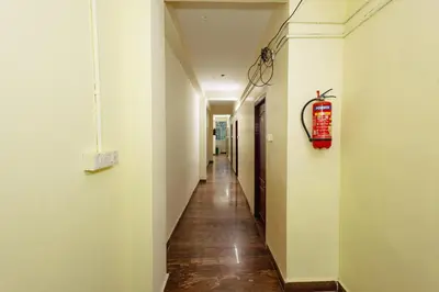 a hallway with white walls and a red fire extinguisher at Pvt Residency in Palani
