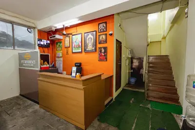 a bar in a restaurant with orange walls and a staircase at Pvt Residency in Palani
