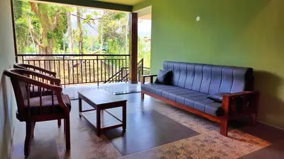 a living room with a couch and chairs and a balcony at Vipinam, The riverside retreat in Kotamangalam